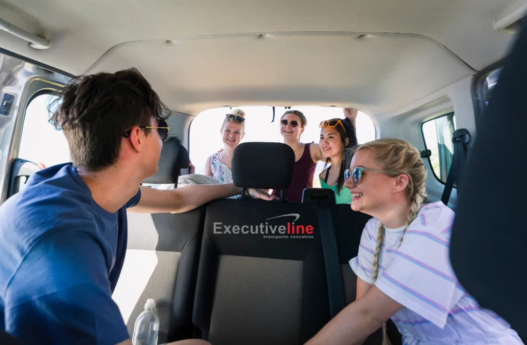 Um grupo de amigos felizes viajam em uma van alugada.