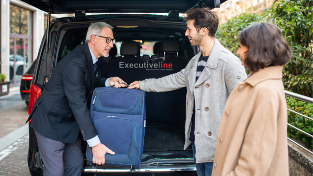 imagem mostra motorista prestativo entregando bagagem aos passageiros ao contrarem uma van para alugar